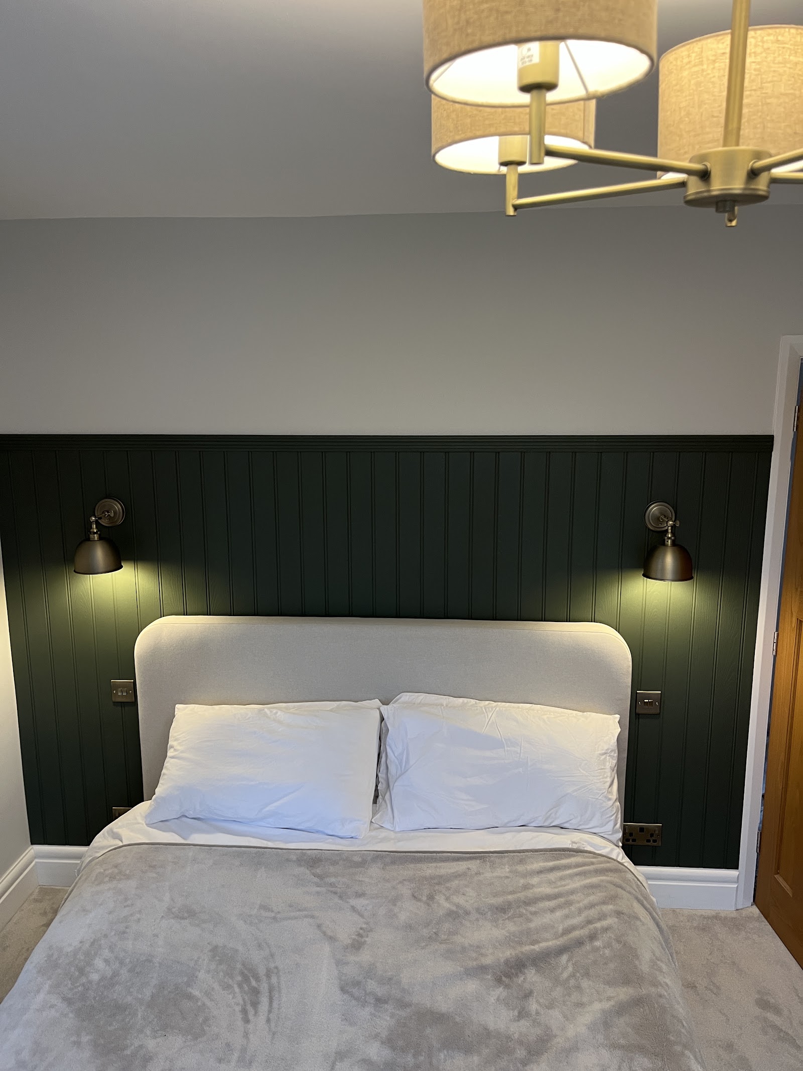 Bedside wall lights and a ceiling fitting wired into a panelled bedroom — switched and positioned around the bed.
